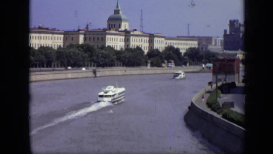 1971 8mm view of the Moscow riverfront, with a white boat on the water and a large domed building beyond the embankment.