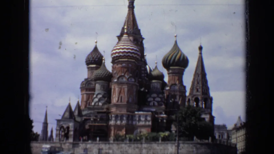 1971 8mm view of St. Basil's Cathedral in Moscow, showing patterned onion domes, brickwork, and spires beneath cloudy sky.
