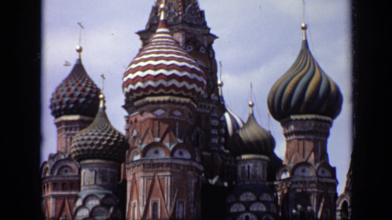 Patterned onion domes and brick towers of Saint Basil's Cathedral against a pale sky.