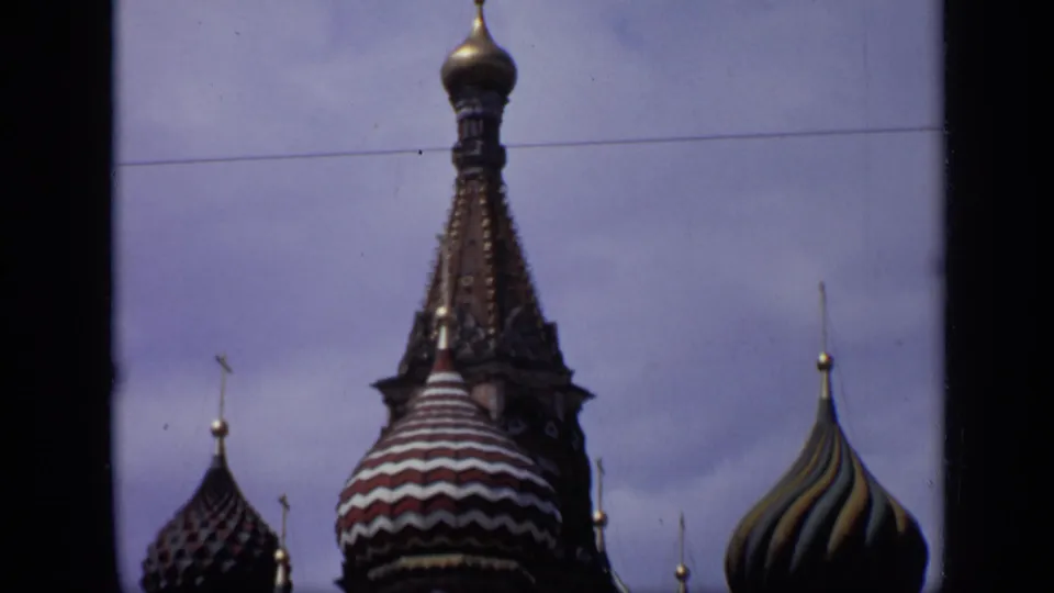 1971 8mm frame showing upper Saint Basil's Cathedral towers and domes in Moscow, with more sky visible above the roofline.