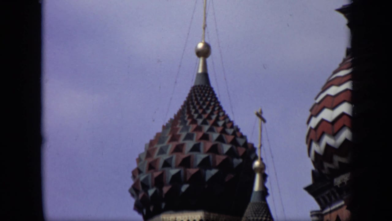 Dark tiled onion dome with a gold finial against pale sky.