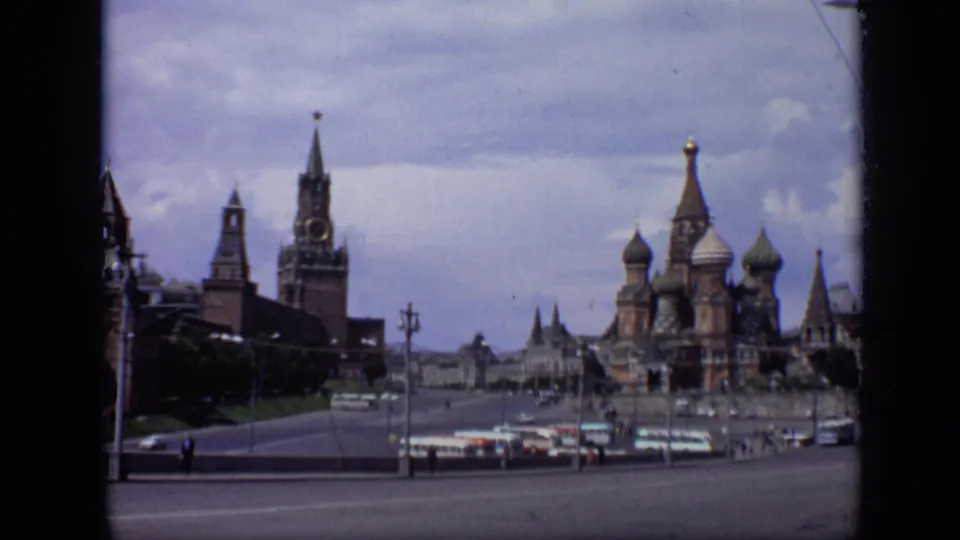 1971 Moscow wide view across Red Square toward St. Basil's Cathedral and the Spasskaya Tower, with buses and small pedestrians below.