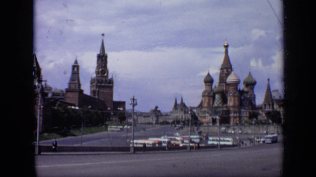 1971 Moscow home-movie frame showing Red Square, Kremlin towers, St. Basil's Cathedral, buses, and small pedestrians.