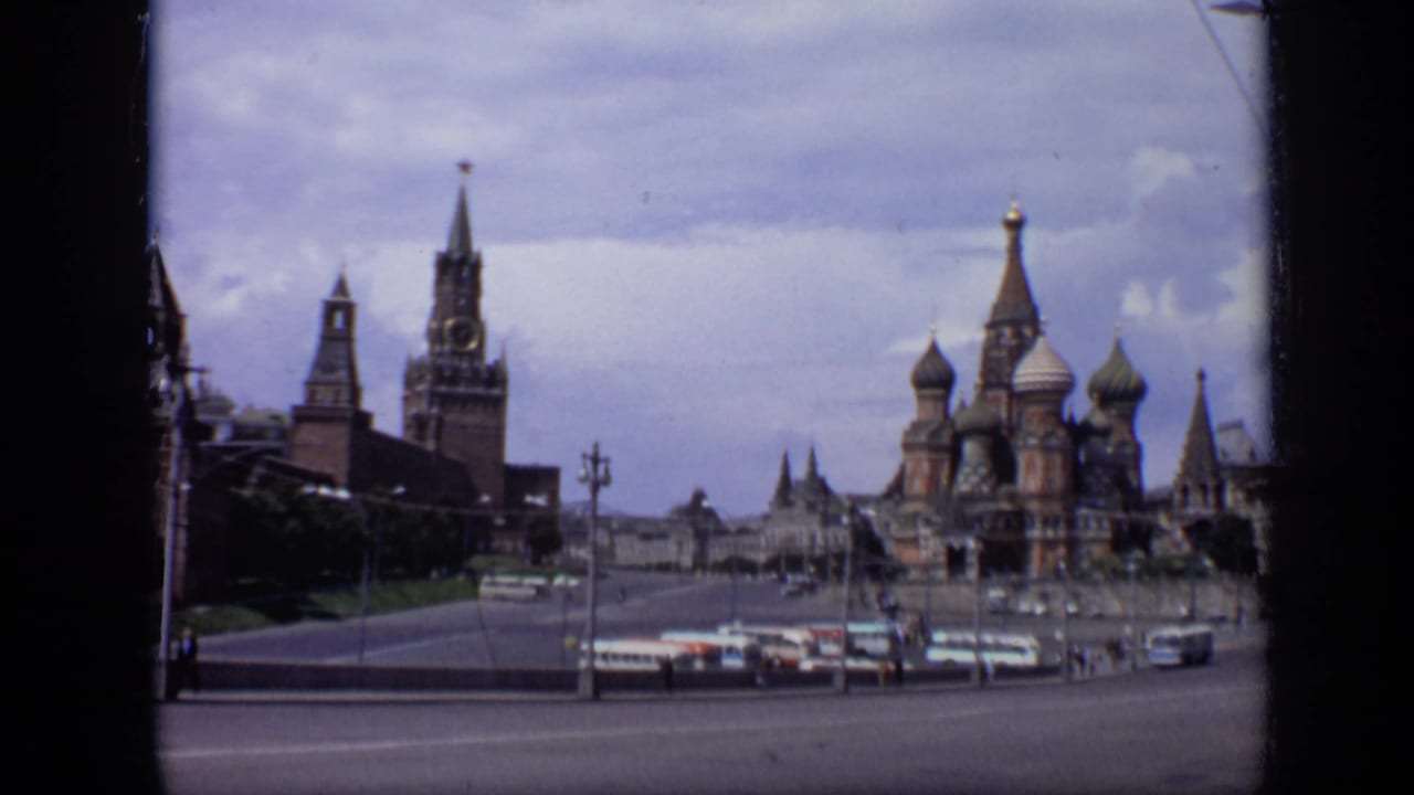 1971 Moscow frame looking across a broad roadway toward St. Basil's Cathedral and Kremlin towers under a cloudy sky.