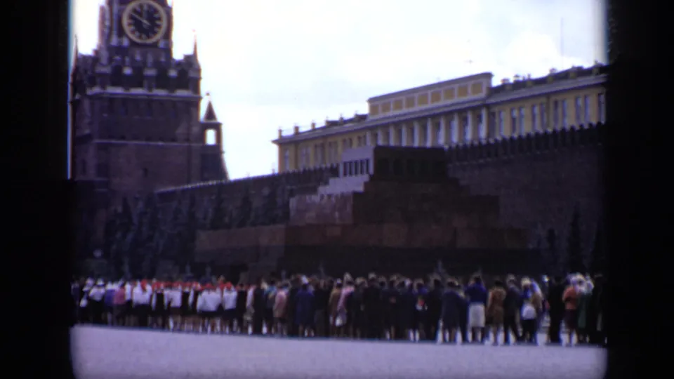 1971 8mm frame of Red Square showing the Kremlin wall, Spasskaya Tower clock, and a large crowd in the foreground.
