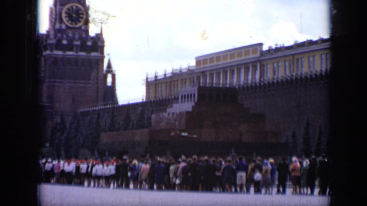 1971 Moscow home-movie frame showing the Kremlin wall, a clock tower, and visitors gathered across Red Square.
