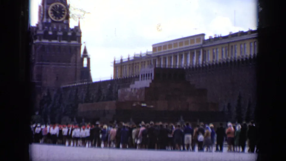 1971 Moscow home-movie frame showing the Kremlin wall, a clock tower, and visitors gathered across Red Square.