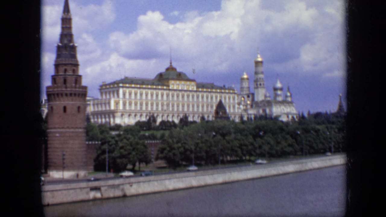 1971 Moscow 8mm frame showing the Kremlin from across the river, with a red brick tower at left and pale buildings behind trees.