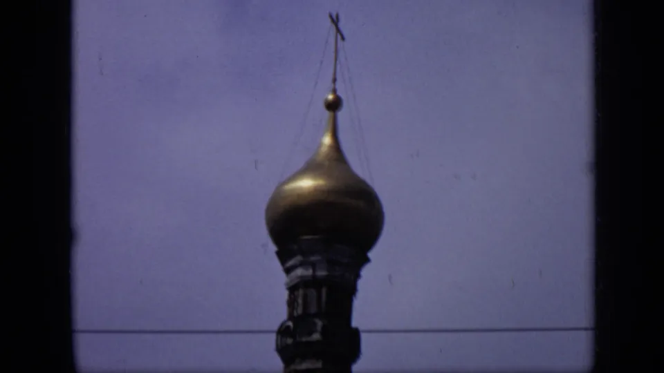 1971 Moscow 8mm frame showing a gilded onion dome topped by a cross, with soft focus, blue sky, and visible film-frame edges.