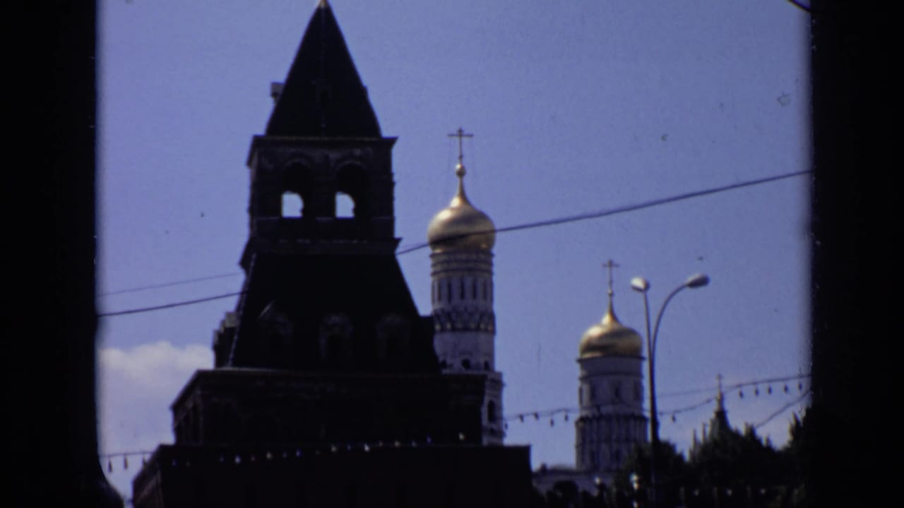 Dark Kremlin tower silhouette with gilded domes and overhead wires.
