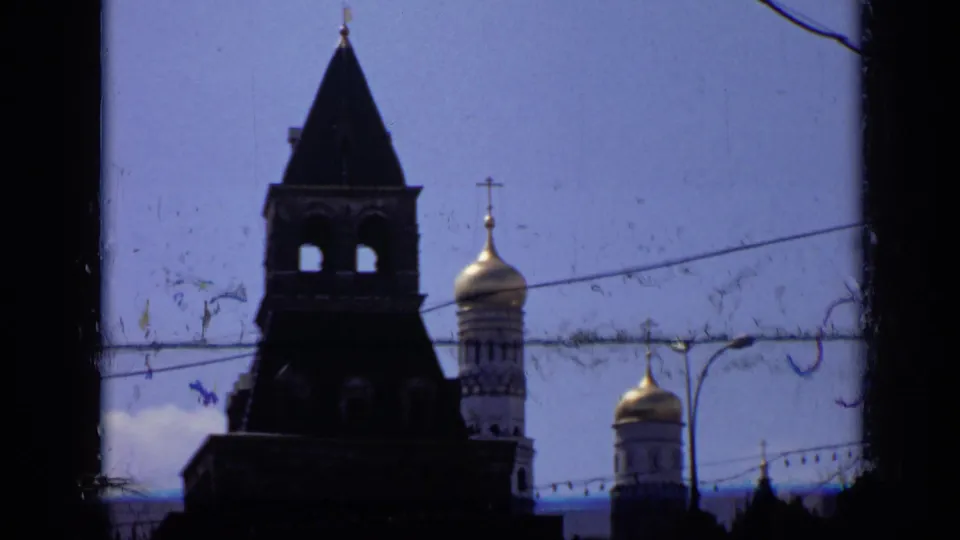 1971 Moscow frame showing a dark Kremlin tower silhouette, gilded onion domes, overhead wires, street lamps, and visible film wear.