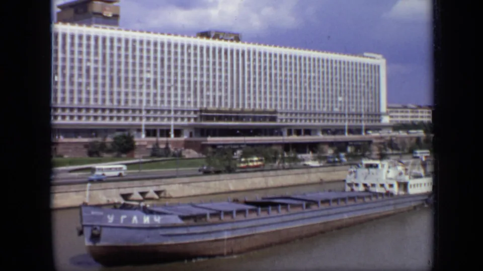 1971 Moscow 8mm frame with the barge nearer the foreground and a large gridded building beyond the embankment traffic.