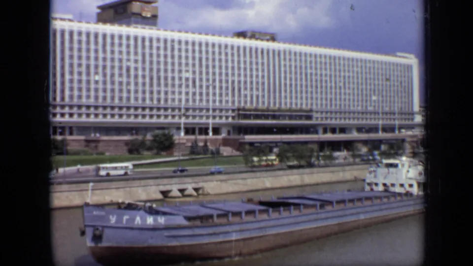 1971 Moscow frame showing the barge partly at right, with buses, cars, embankment, and a large windowed building behind it.