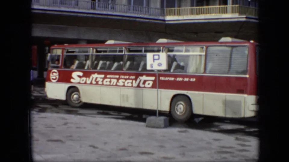 1971 Moscow street-level frame showing the side of a Sovtransavto bus, a parking sign, and the upper floors of a white building.