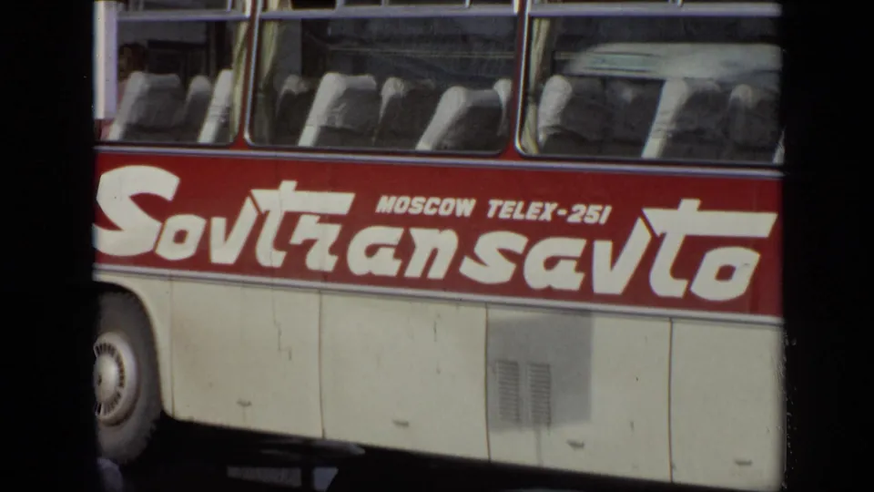 Closer 1971 Moscow frame of the Sovtransavto coach, emphasizing the side lettering, windows, wheel, and cream body panels.
