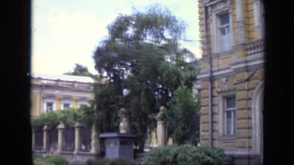 1971 Moscow view of a yellow-toned older building, trees, fence posts, and a small street-side structure.