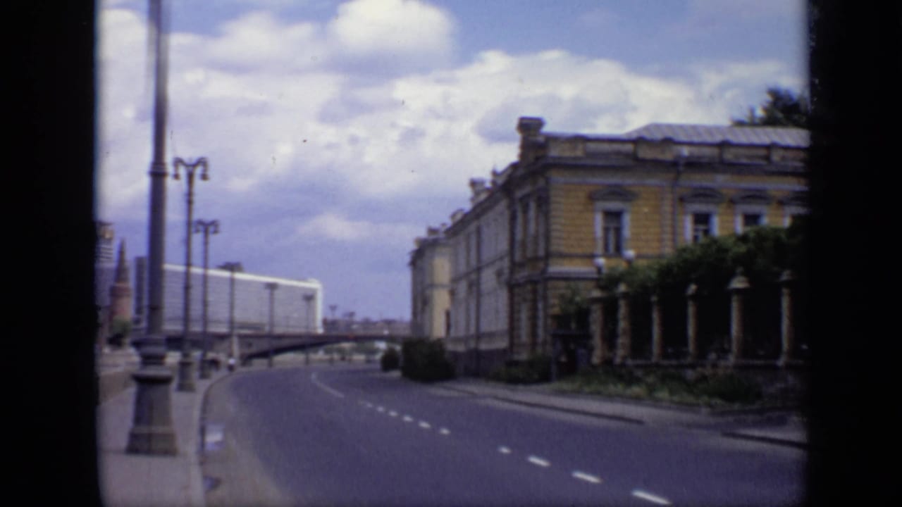 Moscow riverside road in 1971 with tall lampposts, a bridge or overpass, and a classical building along the sidewalk.