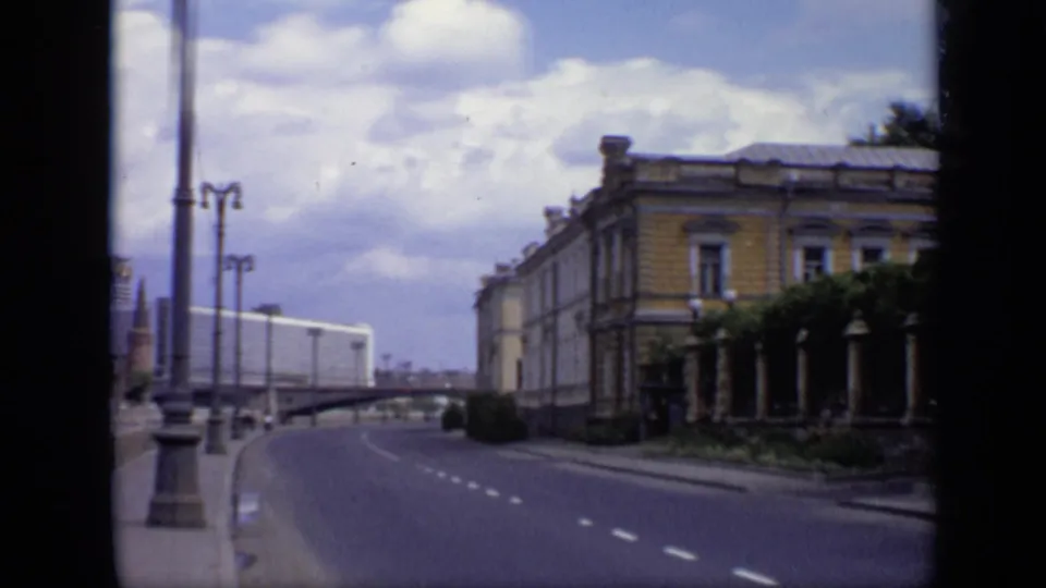 Moscow riverside road in 1971 with tall lampposts, a bridge or overpass, and a classical building along the sidewalk.