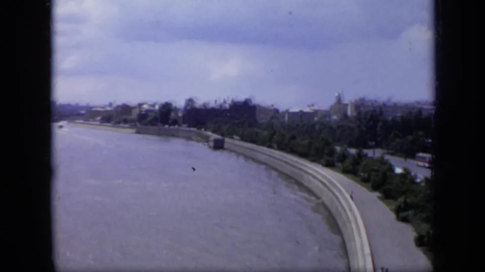 1971 8mm view over Moscow with the river bend, concrete embankment, trees, and distant city skyline under a cloudy sky.