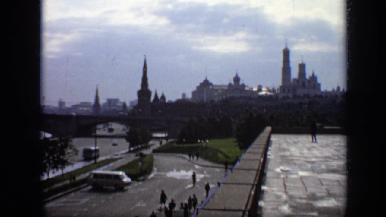 Kremlin skyline and riverfront overlook with wet pavement, pedestrians, and a light-colored van.