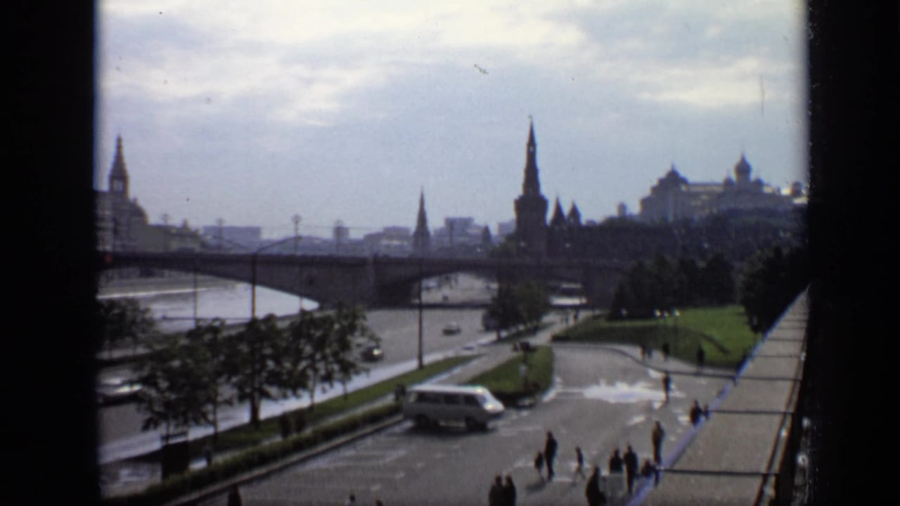 1971 Moscow view from above with a bridge over the river, skyline spires, a white van on the road, and small pedestrian figures.