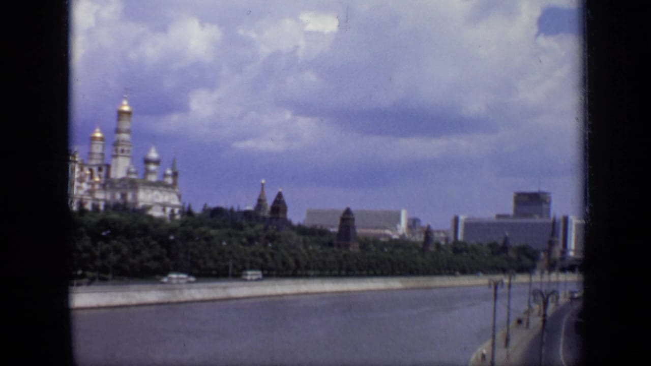 Moskva River view with Kremlin towers and domes under a cloudy sky.