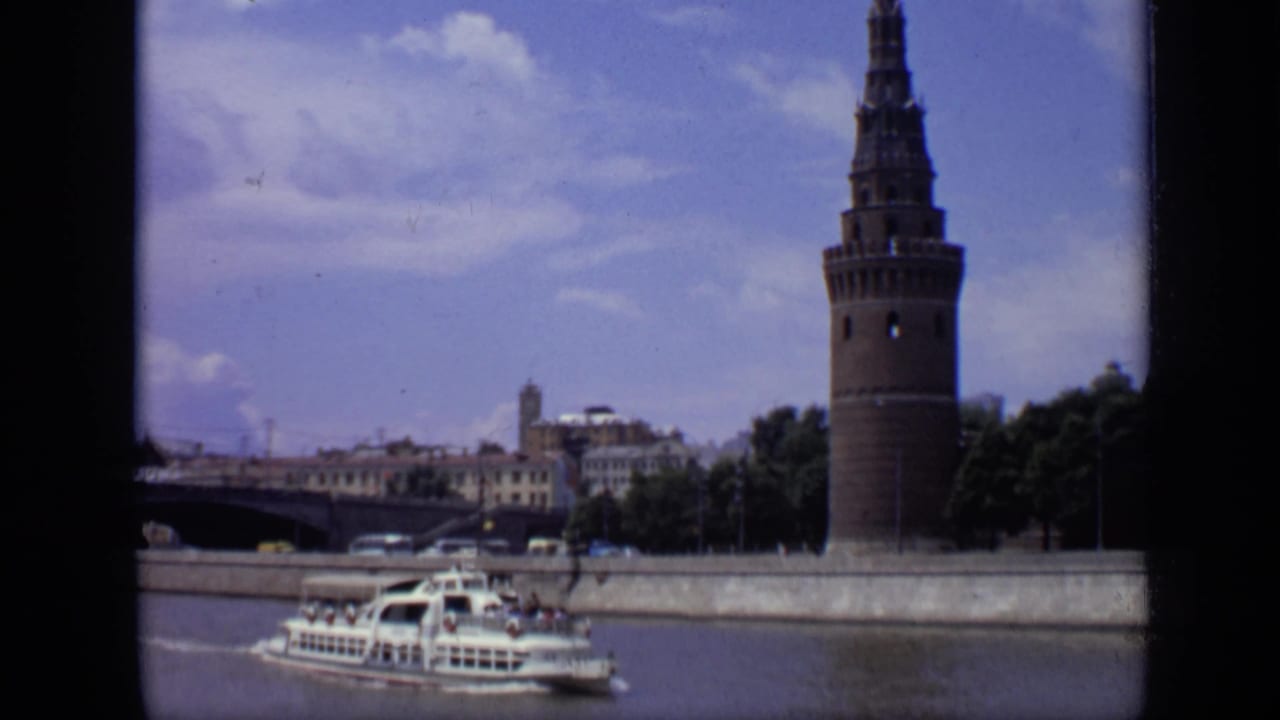 Tour boat traveling on the river with a Kremlin tower and embankment behind it.