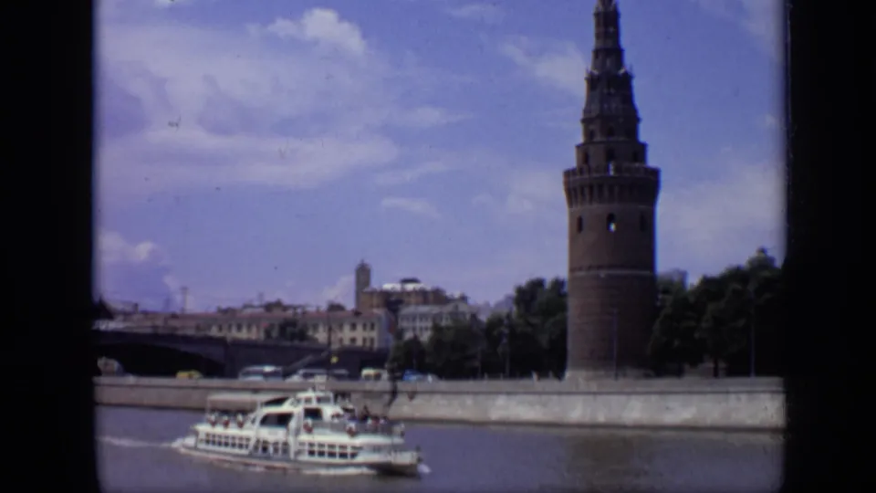 Moscow river sightseeing view from 1971, with a white passenger boat crossing in front of a Kremlin tower and stone embankment.