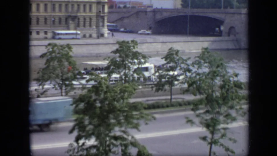 1971 Moscow riverfront seen from above, with cars on an embankment road, trees, a stone bridge, and riverside buildings.