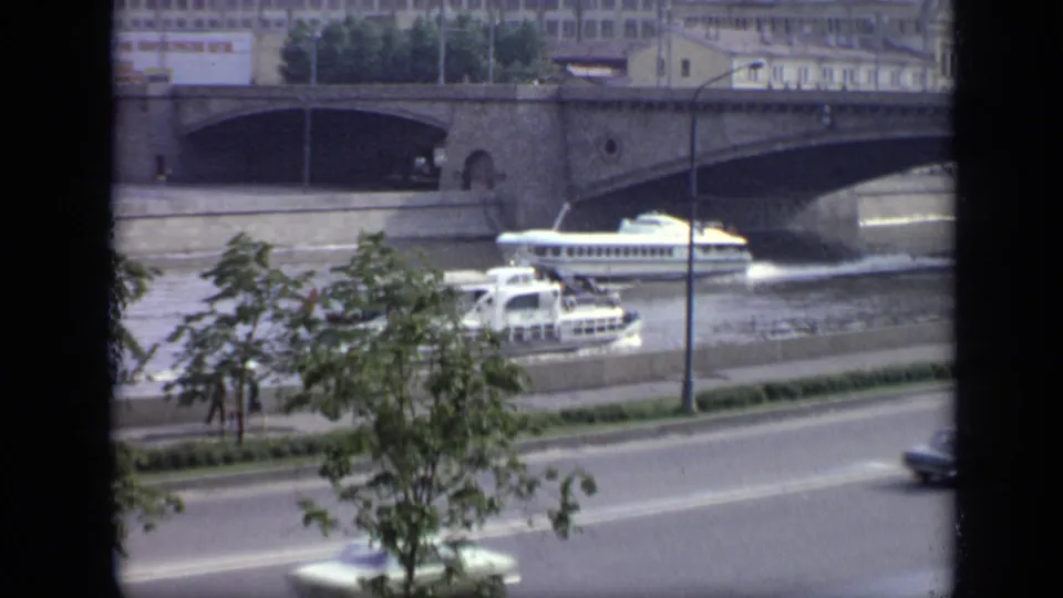 1971 Moscow river scene with white passenger boats near a bridge, trees along the embankment, and cars on the foreground road.