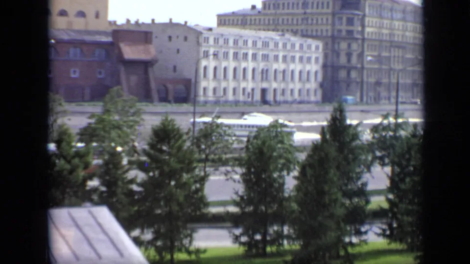 1971 Moscow 8mm view from behind a dark frame toward trees, embankment road, and multi-story buildings.