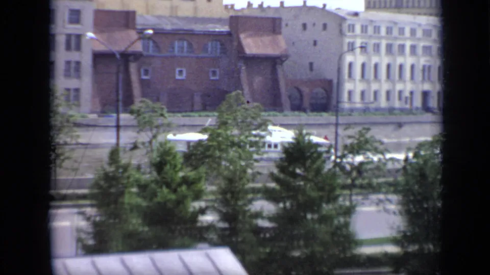 1971 Moscow 8mm frame showing an elevated view of trees, streetlamps, roadway, and Soviet-era urban buildings.