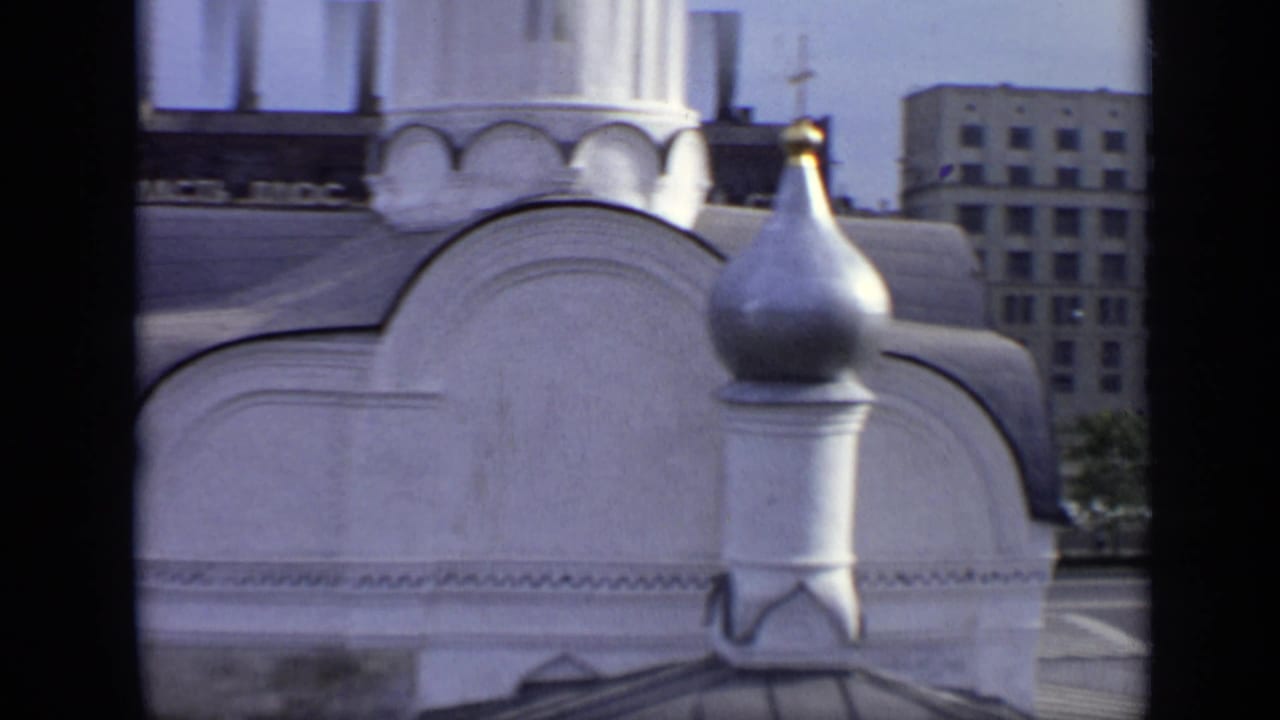 1971 Moscow view of a white ornate dome and metallic finial, with Soviet-era buildings and a riverside road behind it.