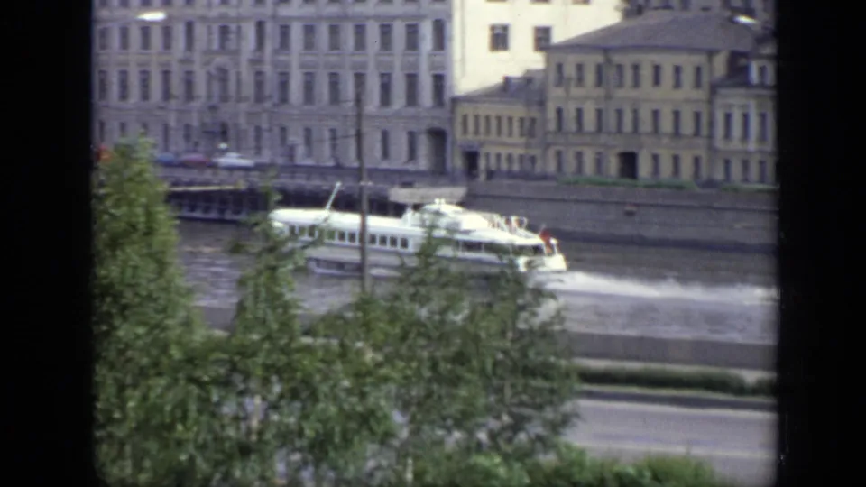 A 1971 Moscow river view shows the hydrofoil partly obscured by leafy trees, with traffic and apartment-like buildings beyond.
