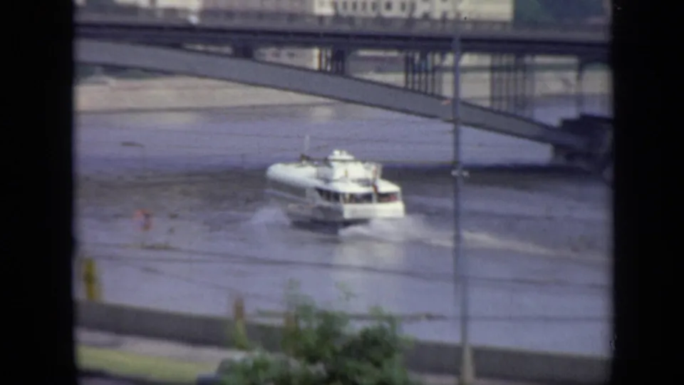 Soft 8mm view of a white riverboat near a bridge over a broad Moscow waterway, with embankment road and foreground window framing.