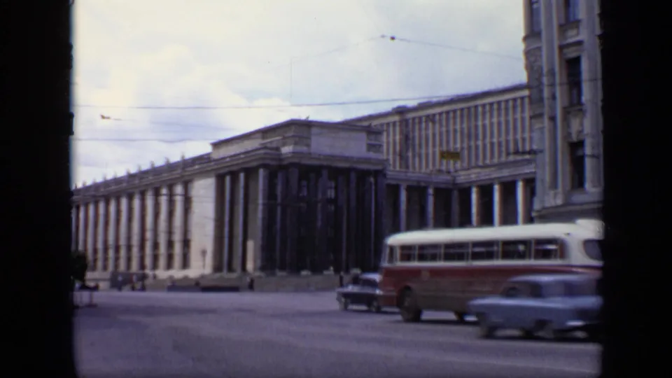 1971 Moscow traffic view with vintage cars, a red-and-white bus, overhead wires, and a large columned public building.