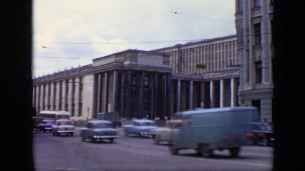 Traffic passing a large colonnaded building on a broad Moscow street.