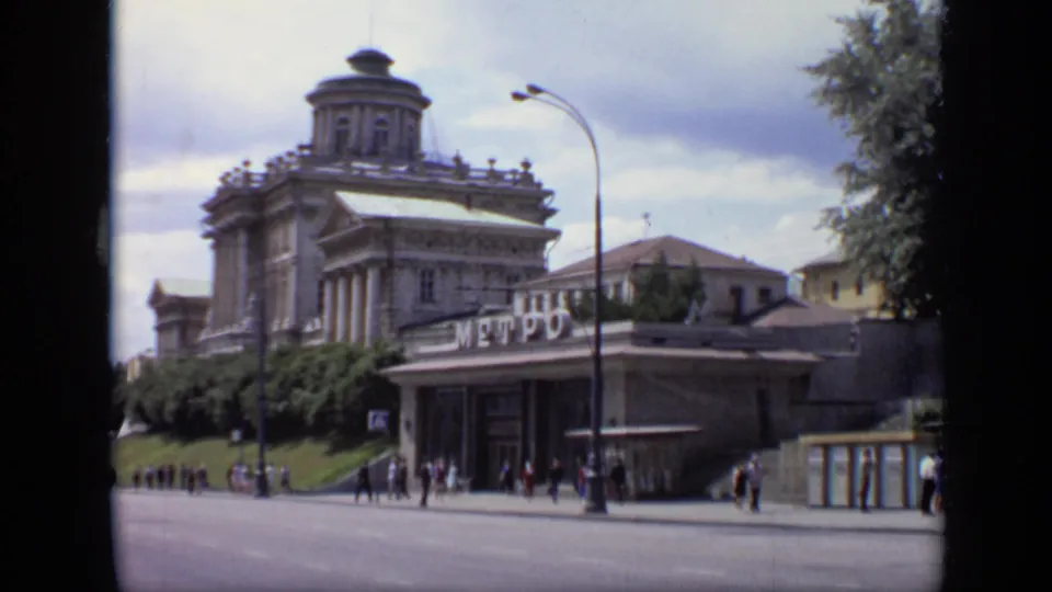 1971 Moscow pedestrians near a metro entrance, with a sign on the entrance and ornate building behind.