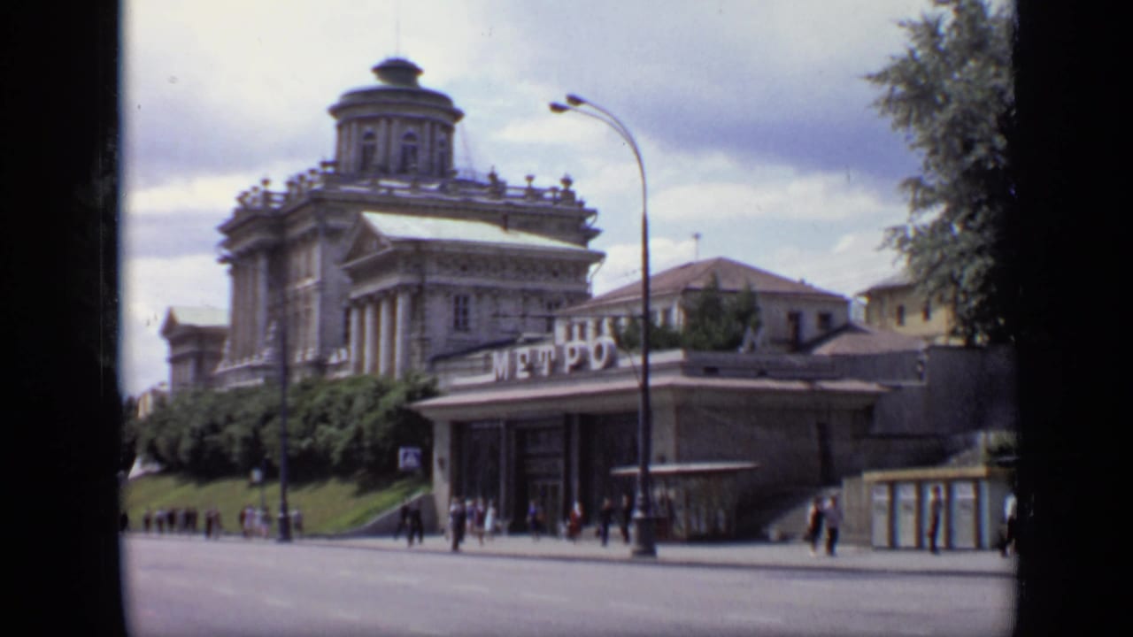 1971 Moscow street view showing a domed classical building, Metro signage, pedestrians, and a broad road under cloudy skies.