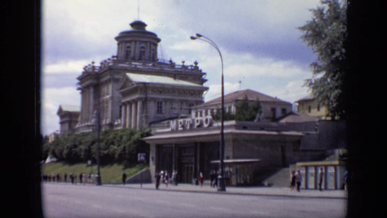 Moscow, 1971, with Cyrillic Metro signage in front of a large domed building and small pedestrian figures on the sidewalk.