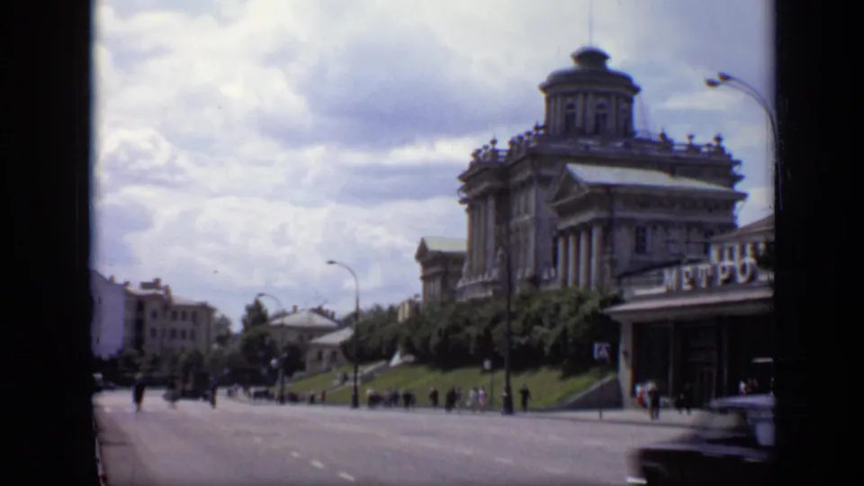 Wider 1971 Moscow street frame showing the Metro entrance at right, a domed building above it, pedestrians, trees, and roadway.
