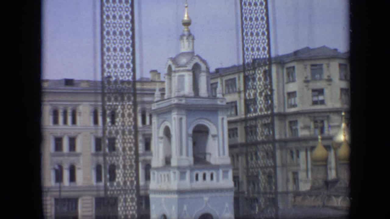 Bell tower, apartment buildings, and golden domes framed by dark film borders.