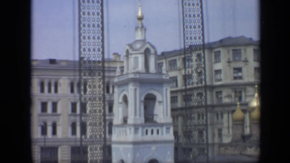 1971 Moscow 8mm frame showing the white tower shifted lower in view, with grille panels, golden domes, and blocky facades.