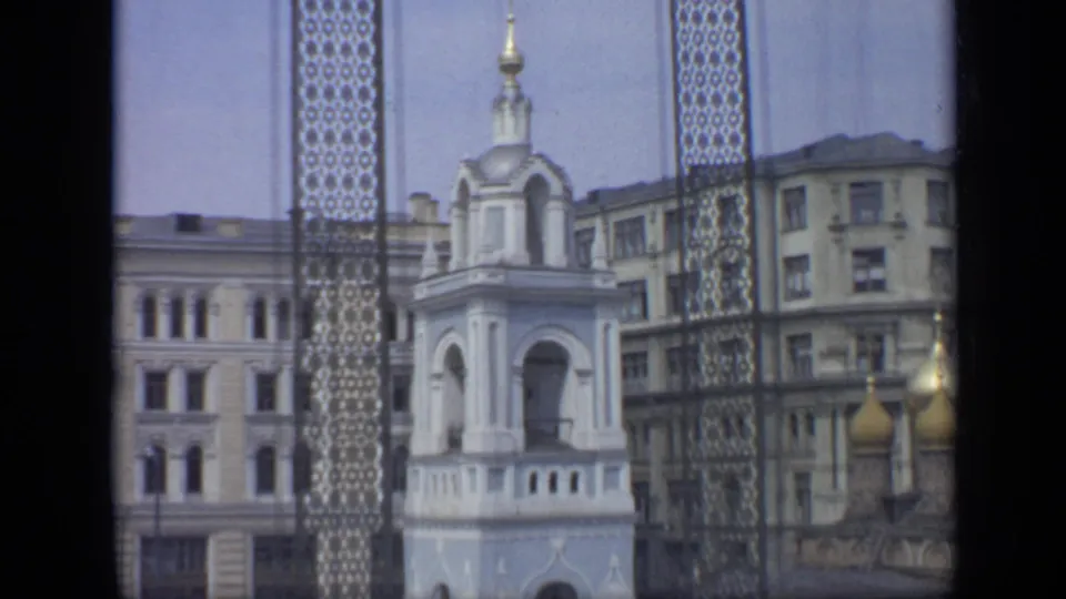 1971 Moscow frame holding on the white bell tower, golden domes, decorative grille, and surrounding Soviet-era apartment facades.