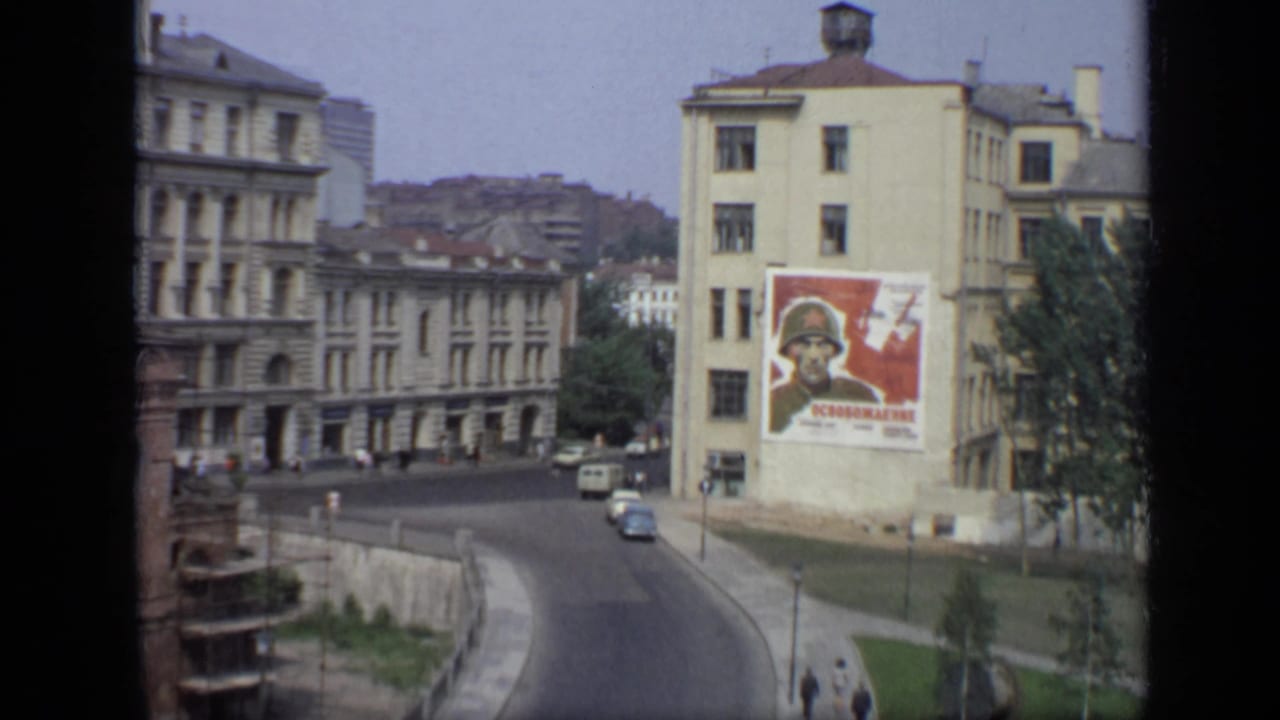 Elevated Moscow street view with curved road, cars, pedestrians, buildings, and a soldier poster.