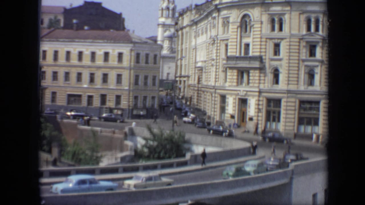 Curved roadway with cars, pedestrians, railings, and ornate buildings in Moscow.