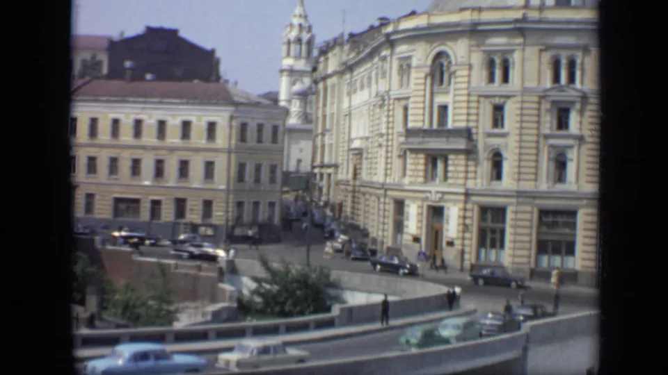 1971 Moscow street corner showing an ornate building facade, parked cars, traffic on a curved road, railings, and pedestrians below.