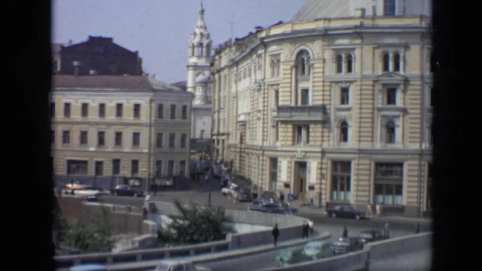 1971 Moscow elevated view with mid-century cars on a curved roadway, pedestrians near railings, and historic stone buildings in the background.