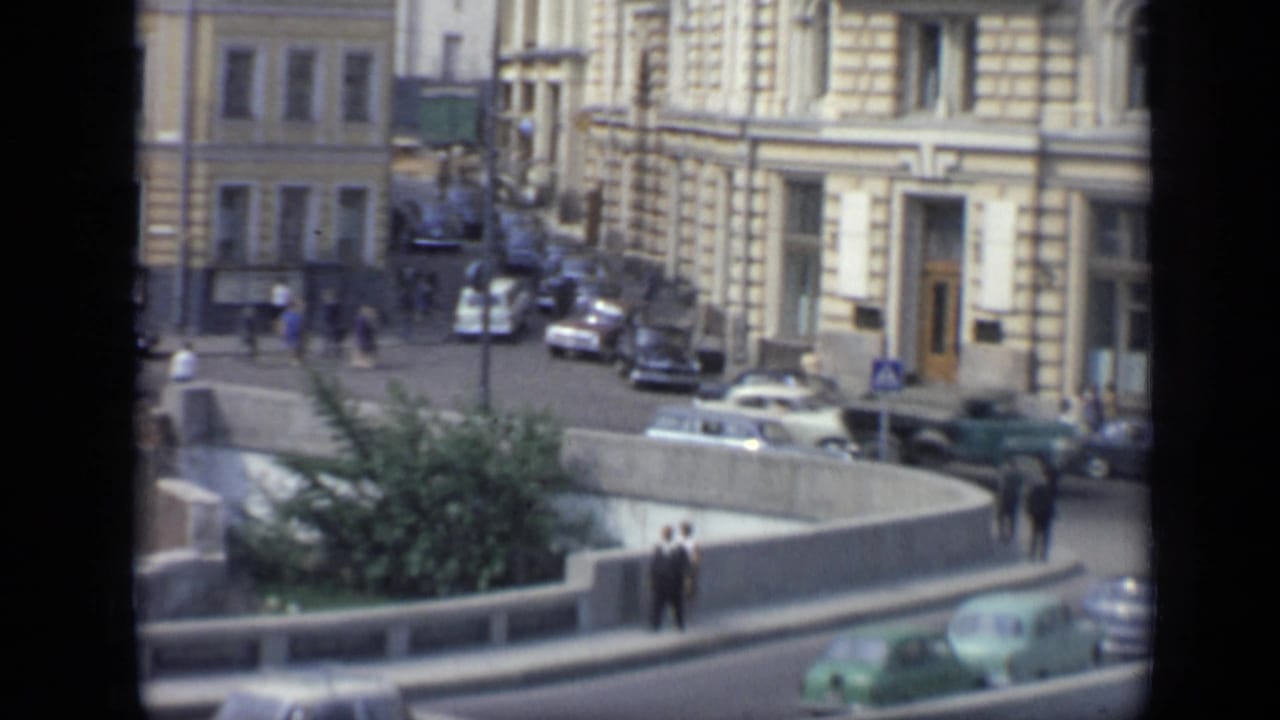 Elevated view of a Moscow street with cars, pedestrians, buildings, and a concrete traffic island.