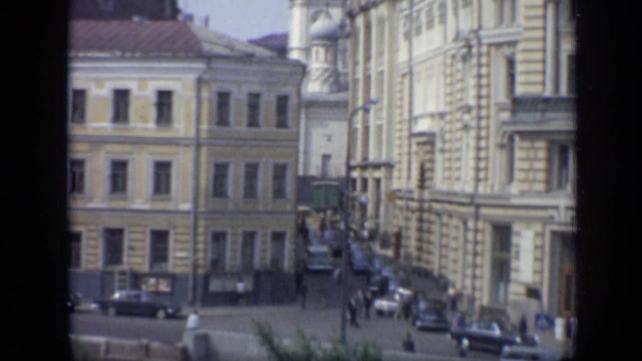 1971 Moscow exterior showing a street corner, older masonry buildings, pedestrians, cars, and visible 8mm frame borders.